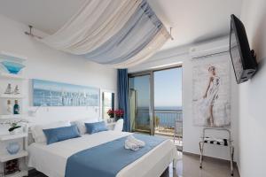 a white bedroom with a bed and a balcony at Contessina del mare in Panormos Rethymno