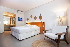 1 dormitorio con 1 cama blanca grande y 1 silla en Hotel Mercedes, en Ilhabela
