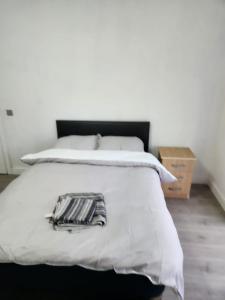 un letto con una coperta bianca e un comodino in legno di Peace House a Streatham Vale