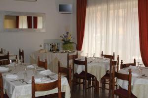 una sala da pranzo con tavoli e sedie bianchi e una finestra di Hotel Solaris a Giulianova