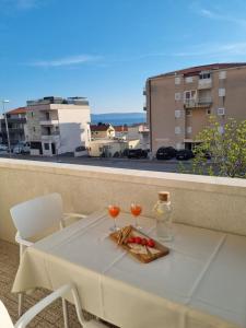 a table with two glasses and a plate of food on a balcony at Apartments Ema near beach in Makarska