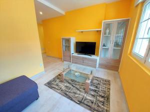a living room with yellow walls and a glass table at Corral da Laxe in Dumbría
