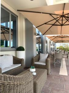 a patio with wicker chairs and tables and umbrellas at Hotel Poppi in Mira