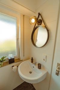 een badkamer met een witte wastafel en een spiegel bij Studio Apartment mit Parkplatz in Oberesslingen