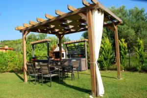 a wooden pergola with chairs and a table in a yard at MyseA VillasNikiti in Nikiti
