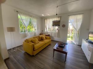 a living room with a yellow couch and a table at Coquette villa privée au bord de l'océan in Pointe aux Cannoniers