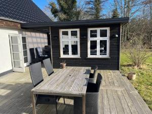 a wooden table and chairs on a deck with a house at Dejligt stort hus med spa in Ålbæk