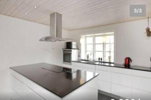 a white kitchen with a stove and a counter top at Dejligt stort hus med spa in Ålbæk