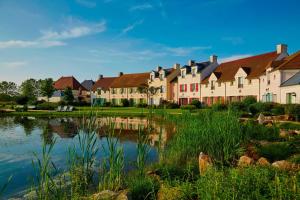a row of houses with a pond in front at 2 Bedrooms Apartment at Village D'ile De France in Bailly-Romainvilliers