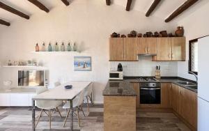 una cocina con armarios de madera, mesa y sillas en Casas Blanca 34 piscina Playa privada wifi, en Tossa de Mar