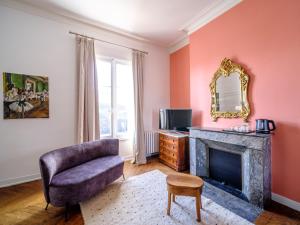 Aux Marquises في سوموور: غرفة معيشة بها موقد وكرسي ومرآة