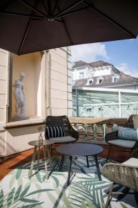 - une terrasse avec 2 chaises, 2 tables et un parasol dans l'établissement Grüne Villa Wellness & Spa, à Bad Kreuznach