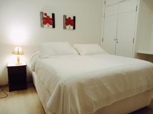 a bedroom with a large white bed with red flowers on the wall at Pousada Morro do Elefante in Campos do Jordão