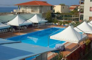 a large swimming pool with white umbrellas on a building at Belvedere Hotel Club in Belvedere Marittimo