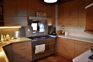 cocina con armarios de madera y horno con fogones en Torre de Arriba Casa Rural, en Benimantell