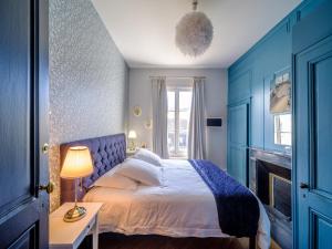 a blue bedroom with a bed and a window at Aux Marquises in Saumur