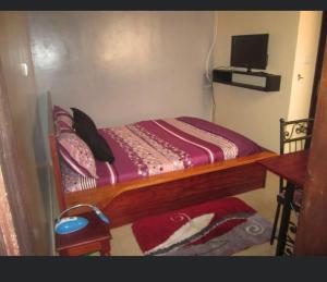 Résidence H في ياوندي: غرفة نوم بسرير خشبي عليها تلفزيون