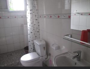 a white bathroom with a toilet and a sink at Résidence H in Yaoundé