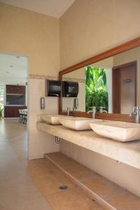 a bathroom with three sinks and a large mirror at Departamento con alberca privada in Chetumal