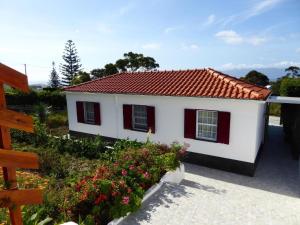uma pequena casa branca com um telhado vermelho em Azorean Cottage São Jorge em Urzelina