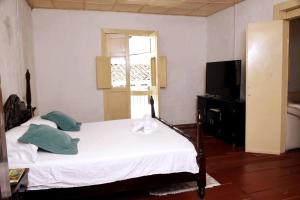 Schlafzimmer mit einem weißen Bett und einem TV in der Unterkunft Casa típica Salamineña in Salamina