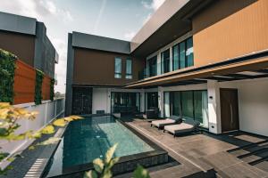 a house with a swimming pool next to a building at Astro Luxury: Ultra Luxury 4 Beds Pool Villa in Nong Prue