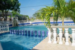 een zwembad met een hek en een palmboom bij Hotel Ayenda Palmas del Río in Mompós