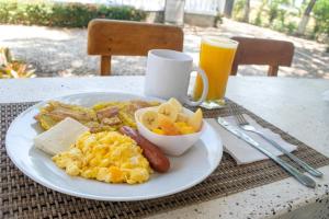 a plate of breakfast food on a table with a glass of beer at Hotel Ayenda Palmas del Río in Mompós