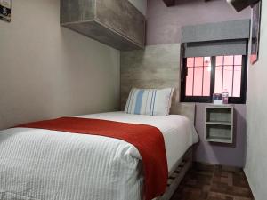 a small bedroom with a bed and a window at Hotel Corazón Mexicano in Guanajuato