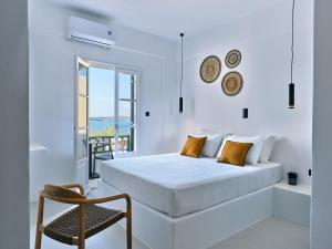 a white bedroom with a bed and a chair at Paros Five Senses in Parikia