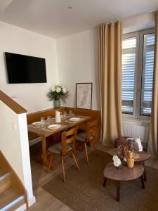 jadalnia ze stołem, krzesłami i telewizorem w obiekcie La Cour du Vignoble w mieście Kaysersberg