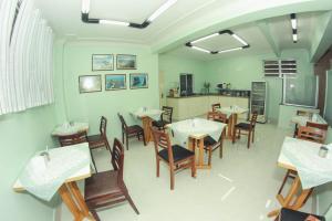 a restaurant with tables and chairs and a kitchen at Alpha Ville Hotel in Assis