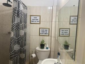 a bathroom with a toilet and a shower with signs on the wall at Cozy Quarters Tobago in Scarborough