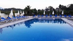 a swimming pool with chairs and umbrellas at Sarban Hotel in Fethiye