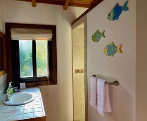 a bathroom with a sink and a window with fish on the wall at Bella Sway Belize in Placencia Village