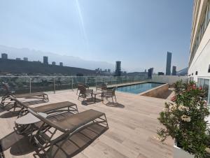 a deck with chairs and a pool on top of a building at Stylish Panoramic Views City Loft in Monterrey