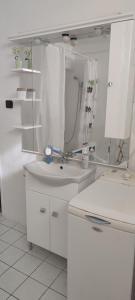 a white bathroom with a sink and a mirror at Nagyi Vendégház Kecskemét in Kecskemét