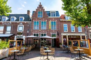a building with tables and chairs in front of it at Hotel Inn Naeldwyk-Torenburg in Naaldwijk