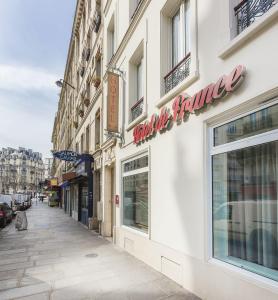 a building with a sign on the side of a street at Hôtel de France Quartier Latin in Paris