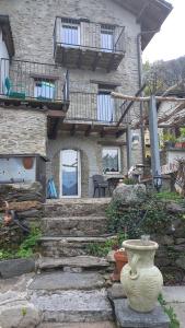 a stone house with stairs and a vase in front of it at Casa Rustica in Magadino