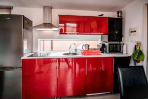 una cucina con armadi rossi e lavandino di Private Paradise on cozy Campsite, Jacuzzi, Netflix a Las Galletas