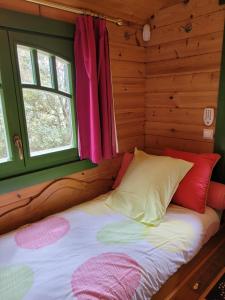 una cama en una cabaña de troncos con ventana en La Roulotte des Oliviers, en Saint-Pierre-de-Vassols