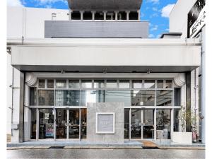 a white building with a sign in front of it at Relief Kokura ANNEX Book & Stay in Kitakyushu