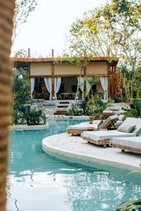 a swimming pool with a resort in the background at Hotel Muaré & Spa Tulum in Tulum