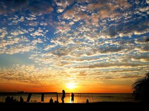 a group of people standing on the beach at sunset at Playa del Ritmo Beach Hostel & Bar - Adults Only in Santa Marta