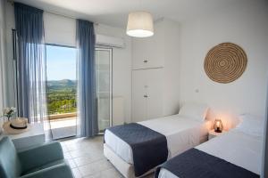 a hotel room with two beds and a balcony at Evianna Studios in Mousata