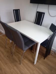 a white table with four black chairs around it at Modern Apartment with Roof Garden Close to City Centre in Cardiff
