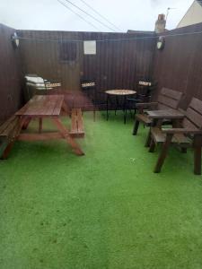 a patio with picnic tables and green grass at Modern Apartment with Roof Garden Close to City Centre in Cardiff