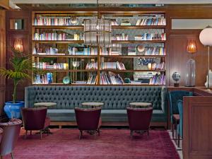 a library with a green couch and shelves of books at Boutique Hotel H10 Villa de la Reina in Madrid