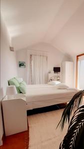 a white bedroom with a large bed and a window at SUN & SAND GUESTHOUSE in Esposende